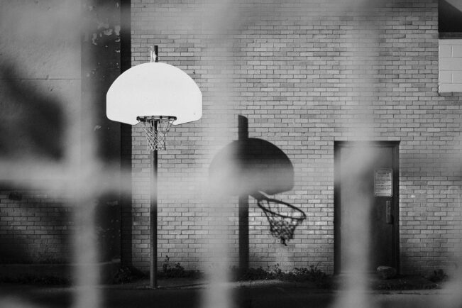 A playground basketball hoop lowered in black and white